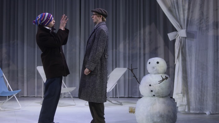 Zwei Männer und ein Schneemann auf einer Bühne