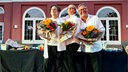 Drei Personen mit Blumensträußen auf der Bühne