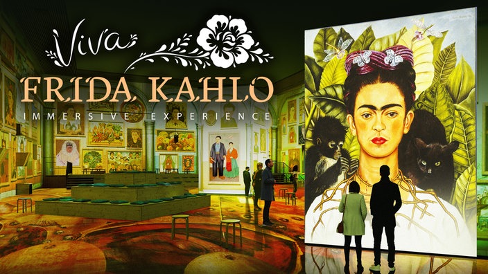 Das Bild zeigt eine farbenfrohe Ausstellung mit vielen Gemälden Frida Kahlos. Im Vordergrund rechts im Bild ist ein Selbstporträt von ihr zu sehen, davor stehen einige Besucher. Die Aufschrift "Viva Frida Kahlo, immersive Experience" ist außerdem zu sehen