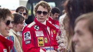 Eine Szene des Films "Rush – Alles für den Sieg": Der Schauspieler Daniel Brühl als Niki Lauda Autogramme gebend in roter Rennfahrer-Montur