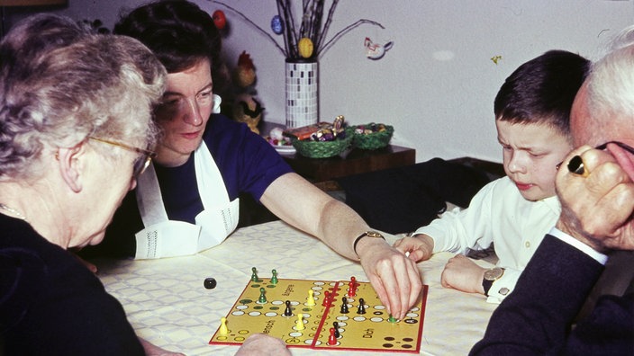 60er Jahre: Eine Familie spielt Mensch ärgere Dich nicht. Im Hintergrund sieht man einen Osterstrauch.