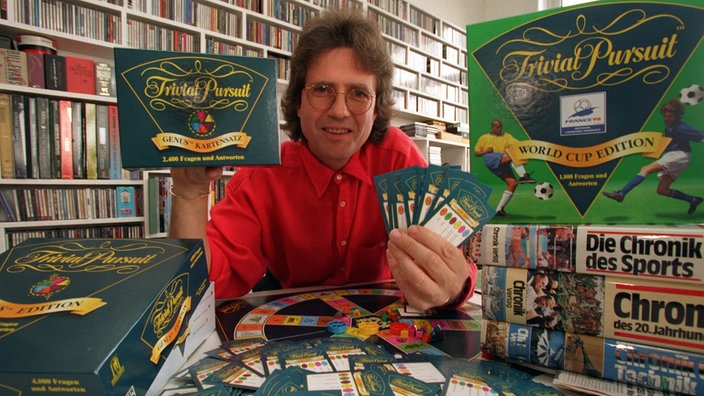 Willi Andresen hält in seinem Hamburger Büro eine Ausgabe von Fragen und Antworten für das Spiel "Trivial Pursuit" in den Händen (1997)