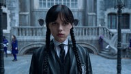 Jenna Ortega als Wednesday Addams steht in der zweiten Staffel der Netflix-Serie "Wednesday" auf dem Schulhof und schaut grimmig in die Kamera. 