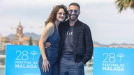 Katia Fellin und Miguel Ángel Silvestre beim Malaga Film Festival. Beide sind lässig gekleidet, tragen Sonnenbrillen, haben den Arm um den anderen gelegt und lächeln freundlich in die Kamera.