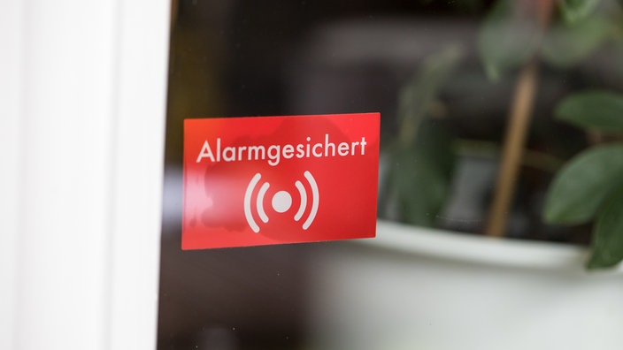 Eine Terassentür mit einem roten Aufkleber, der darauf hinweist, dass das Grundstück alarmgesichert ist