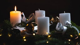 Die erste Kerze brennt auf einem Adventskranz