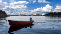 Ein leeres, kleines Holzboot auf einem großen See.