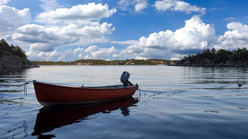 Ein leeres, kleines Holzboot auf einem großen See.