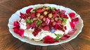 Teller mit Pavlova. Darauf sind verschiedene Beeren angerichtet. 