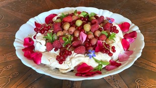Teller mit Pavlova. Darauf sind verschiedene Beeren angerichtet. 