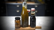 Drei Gefäße mit selbst gemachter Würzsauce stehen auf einem Holzbrett