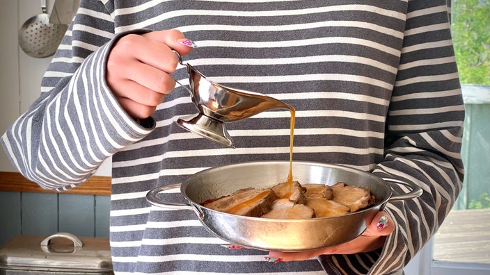 Eine Schale mit Schweinenackenstücken wird mit Soße übergossen.