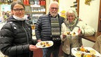 Drei Personen in einem Bistro mit gefüllten Tellern