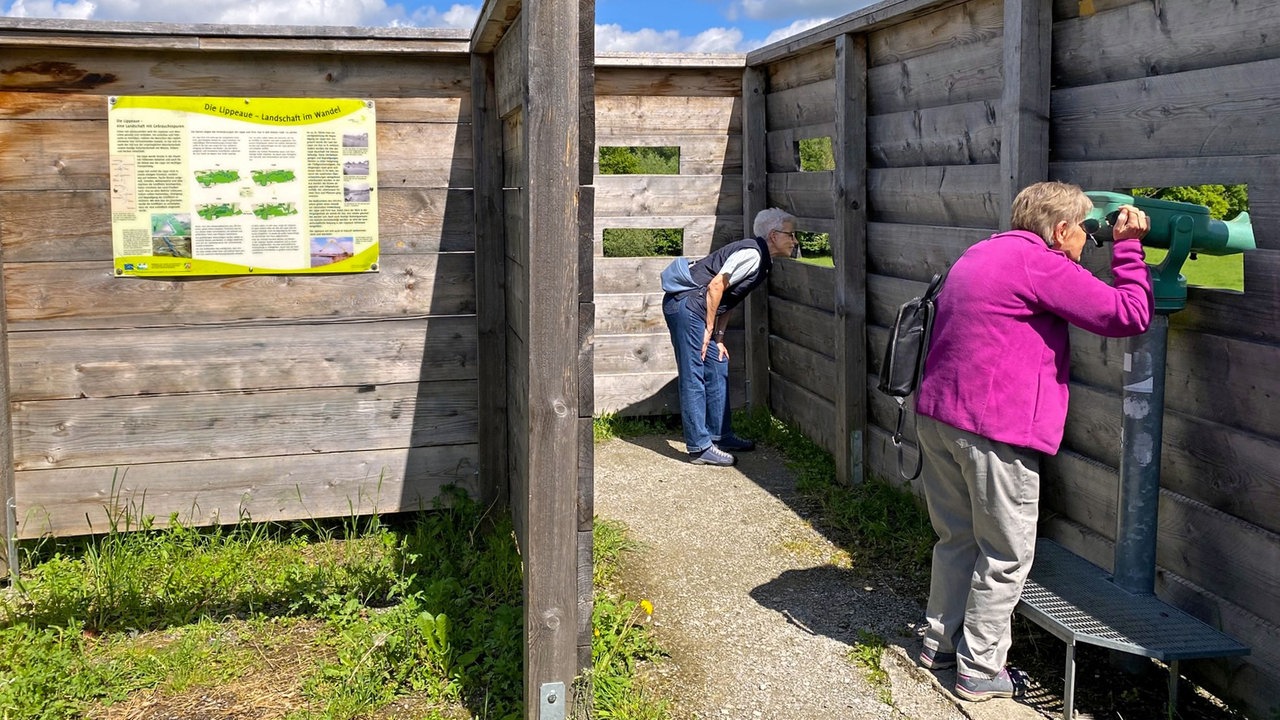 Zwei Personen nutzen die Beobachtungsstation auf einem Aussichtshügel in den Lippe-Auen bei Hamm 