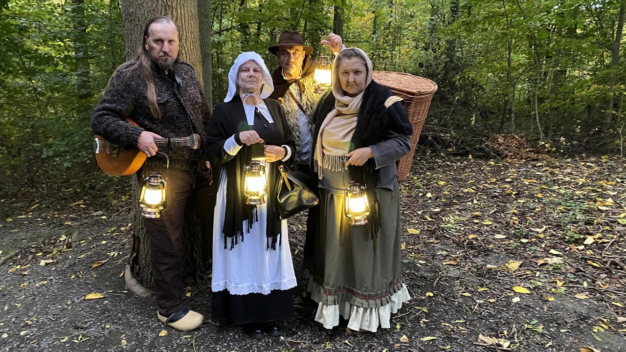Verkleidete Darsteller mit Laternen im Wald
