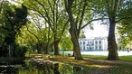 Blick in den Kurpark mit kleinem See im Vordergrund und der Kaiserpalais von Bad Oeynhausen im Hintergrund