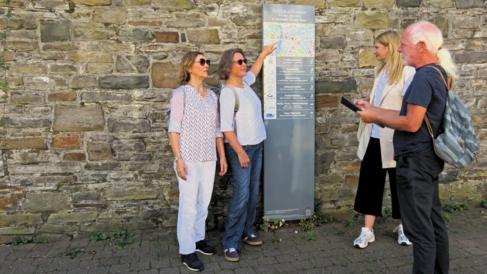 Die Gruppe der "Flunker-Tour" steht an einer Info-Tafel vor einer Mauer