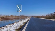 Ein Schiffahrtszeichen am Rande des Kanals: Ein hochkant-orientiertes blaues Rechteck, schräg weiß durchgestrichen. 