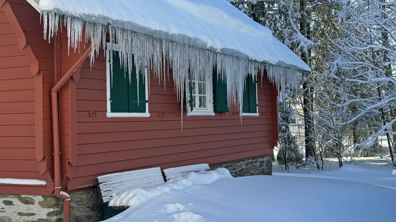 Eiszapfen am Dach eines Hauses mitten im Wald am Wanderweg bei Hoheleye