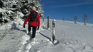 Ein Wanderer in roter Jacke im hohen Schnee 