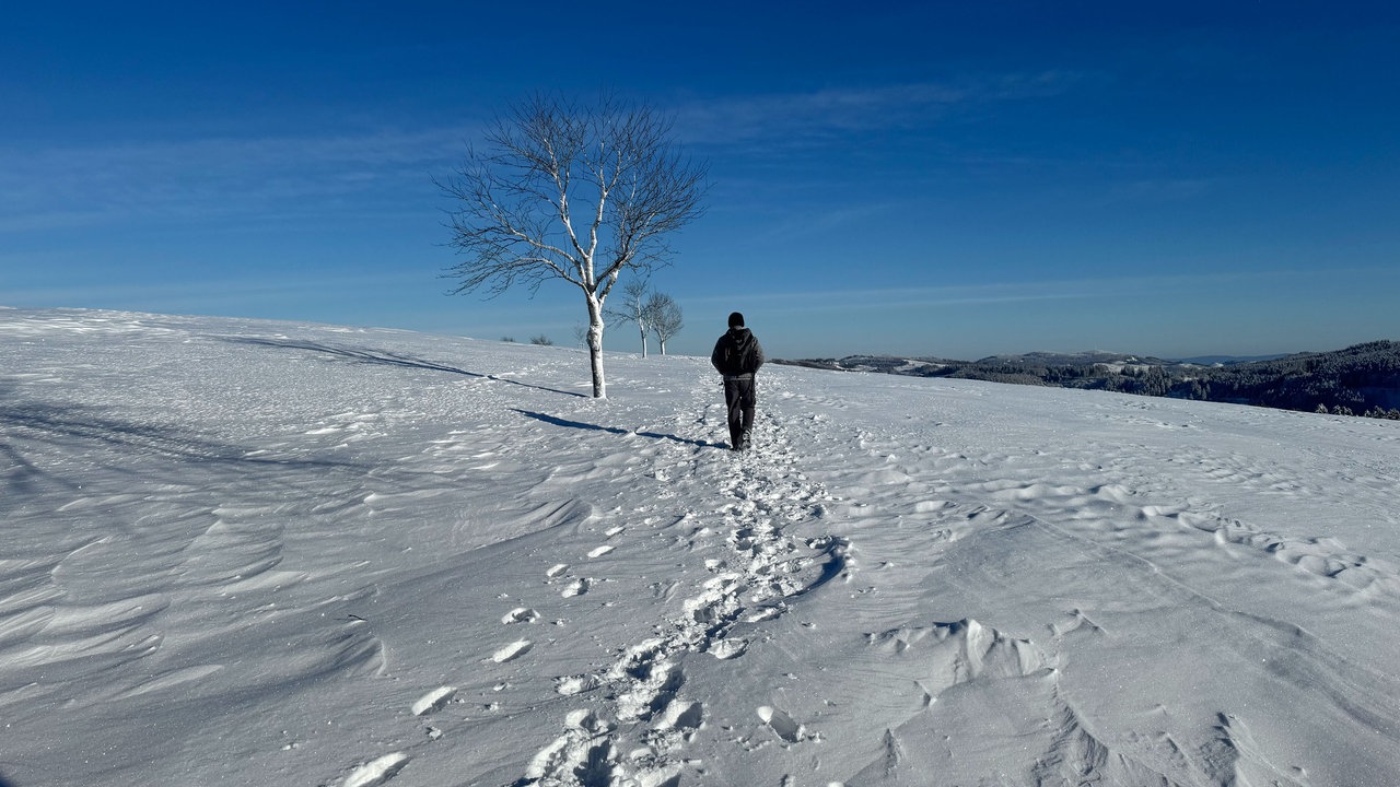 Ein Wanderer in der Winterlandschaft unter blauem Himmel