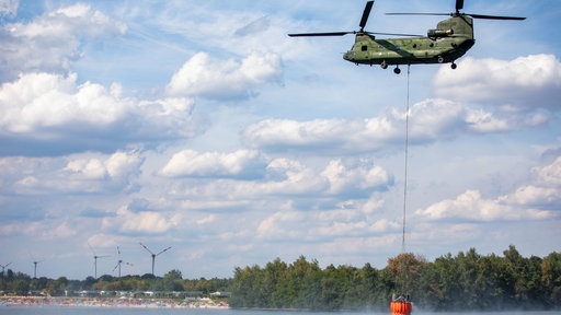 04.08.2018, Nordrhein-Westfalen, Straelen: Etwa 120 Feuerwehrkräfte aus Deutschland und den Niederlanden bekämpfen einen Waldbrand in Straelen mit einem Löschhubschrauber