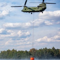 04.08.2018, Nordrhein-Westfalen, Straelen: Etwa 120 Feuerwehrkräfte aus Deutschland und den Niederlanden bekämpfen einen Waldbrand in Straelen mit einem Löschhubschrauber