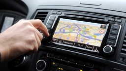 Ein Mann bedient das Navigationsgerät seines Autos während der Fahrt