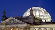Reichstag mit hell erleuchteter Kuppel im nächtlichen Berlin