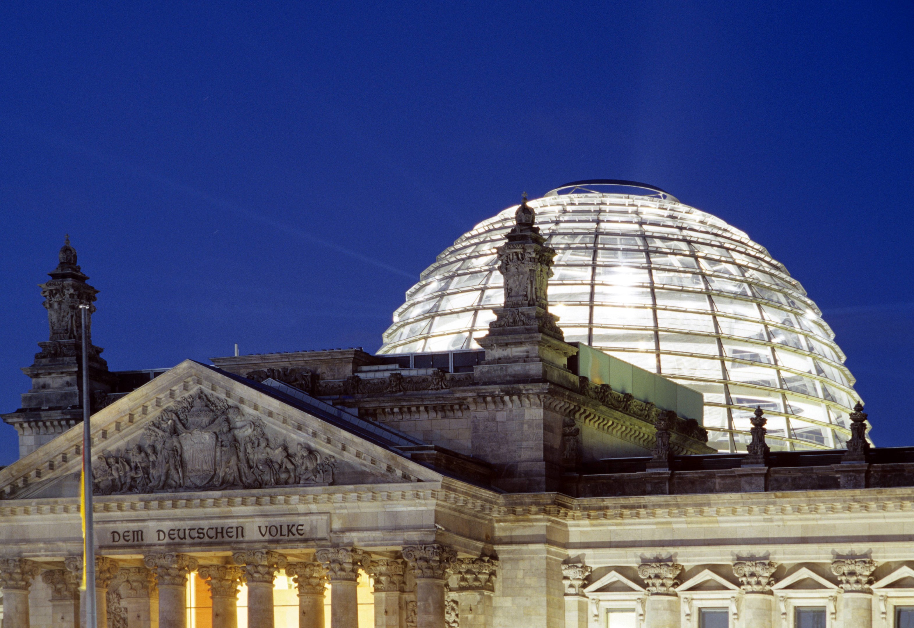 Reichstag mit hell erleuchteter Kuppel im nächtlichen Berlin