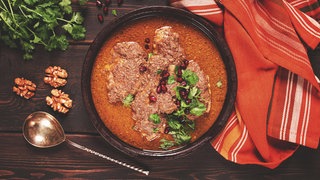Fesenjan, geschmortes Huhn in Walnuss-Granatapfelsoße, ein iranisches Gericht in einer irdenen Pfanne