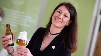 Bier Sommelière Jutta Knoll posiert mit einer Flasche und einem Glas Bier.