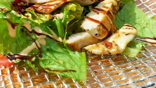 Salat mit Dressing und Fleischstücken, Aussehen kann vom Rezept abweichen. 