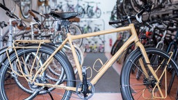 Ein beiges Fahrrad in einem Fahrradgeschäft. Mehrere Fahrräder im Hintergrund