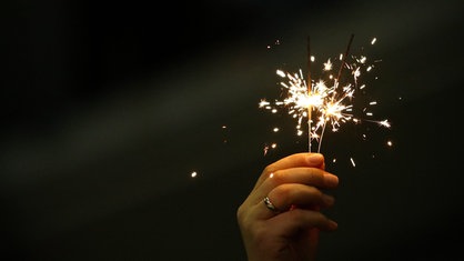 Eine Hand hält zwei brennende Wunderkerzen
