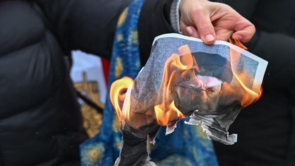 Eine Demonstrantin hält auf einer Solidaritätskundgebung in Paris am 11. Januar 2026 ein brennendes Foto von Ayatollah Khamenei in die Kamera
