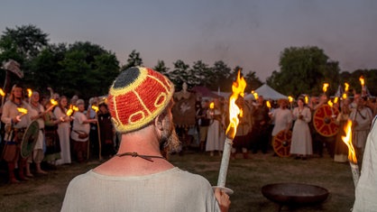 Beim Wikingertag in Schleswig am 12.08.2022 stehen Menschen in historischer Gewandung mit Fakeln im Kreis