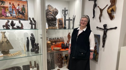 Die Ordensoberin Schwester Angela Maria steht im Überseecontainer der Ausstellung "Räume öffnen" vor Vitrinen mit Artefakten aus der Missionssammlung