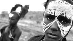 Das Beitragsbild des Dok5 "Grüner Kolonialismus" zeigt einen jungen Massai mit weißer Gesichtsbemalung in 2016
