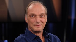 Porträtaufnahme von Schauspieler Martin Brambach in blauem Hemd am 26.8.2022 vor der NDR Talk Show N3.