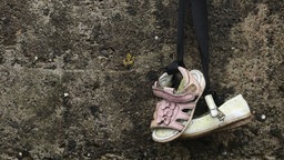Ein paar Kinderschuhe hängt zum Gedenken an einer Wand nahe dem Kinder-Massengrab in Tuam