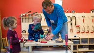 Ein Erzieher werkelt mit zwei Kindern in einer Kita.
