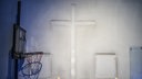 Ein mobiler Basketballkorb steht vor dem Umriss eines abgehängten Kreuzes an einer Wand in der entweihten katholische Kirche St. Josef in Gelsenkirchen-Ueckendorf im Rahmen der Kunstschau Manifesta 16 Ruhr.