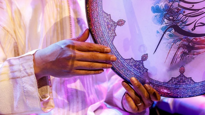 Die Hände eines Sufis schlagen eine kunstvoll illustrierte Handtrommel