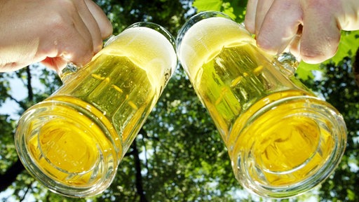 Von unten - es wird mit zwei Biergläsern angestoßen.