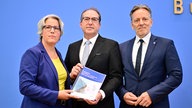 Kerstin Claus, Bundesbeauftragte gegen sexuellen Missbrauch, Innenminister Alexander Dobrindt und Holger Münch, Präsident des Bundeskriminalamtes, halten auf einer Pressekonferenz das gedruckte Bundeslagebild zu sexueller Gewalt an Kindern in den Händen