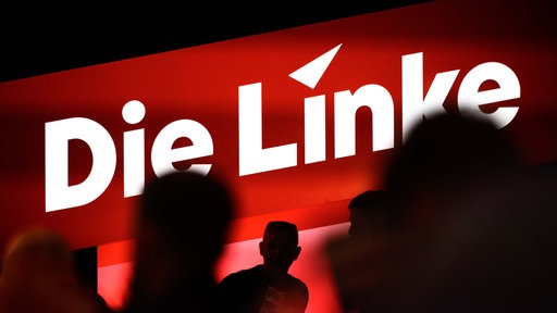 Delegierte sitzen auf dem Bundesparteitag unter dem Logo der Partei "Die Linke". 