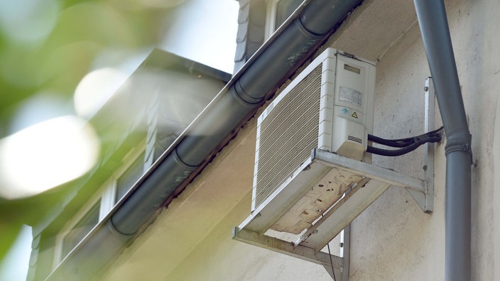 Eine Klimaanlage hängt in Essen an der Hauswand eines Mehrfamilienhauses. 