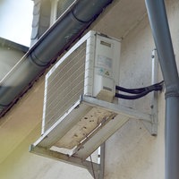 Eine Klimaanlage hängt in Essen an der Hauswand eines Mehrfamilienhauses. 