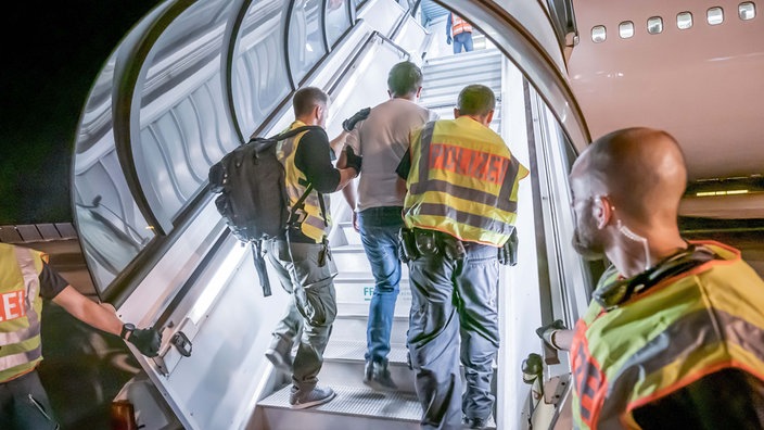 Archivbild: Polizeibeamte bringen einen AMenschen aus Afghanistan auf dem Flughafen Leipzig-Halle in ein Charterflugzeug (2020)